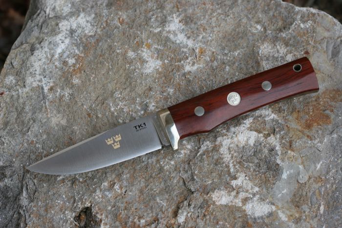 Couteau »TK1« de Fällkniven; acier / bois, satiné, avec manche Cocobolo; poids net: 187 g; epaisseur de lame: 4.5 mm; longueur totale: 215 mm; longueur de lame: 100 mm; acier de lame: 3G; avec étui en cuir noir; poids brut: 820 g